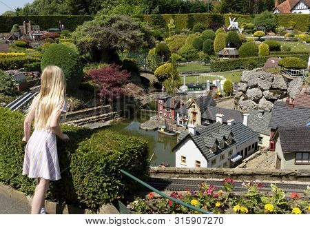 Beaconsfield, Uk - June 27, 2019. A Young Girl Visitor Looks At Miniature Houses In Bekonscot Model 