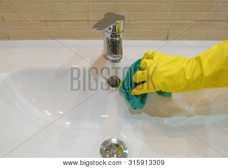 Woman In Yellow Rubber Gloves Cleaning A Sink. Housewife Holding A Rag. White Sink. Modern Bathroom.