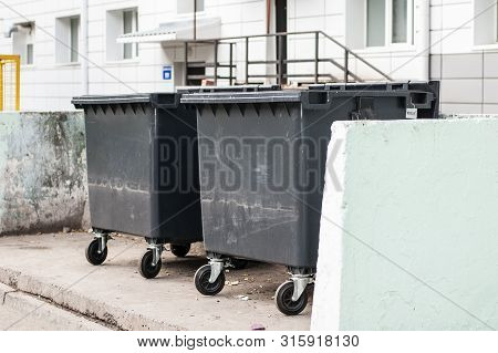 Dumpsters On The Grey Wall Background. Garbage Bins Near Housing