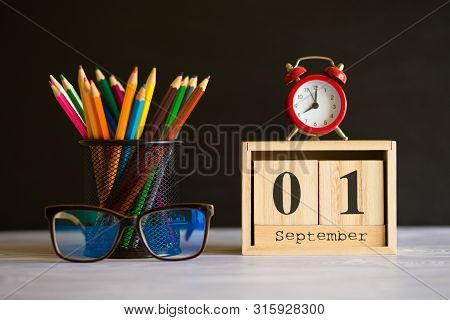 Concept Back To School. Re Alarm Clock With Color Pencils And Wooden Calendar Set On 1St September O