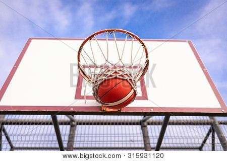 Basketball Board With Basket Hoop Against Blue Sky.