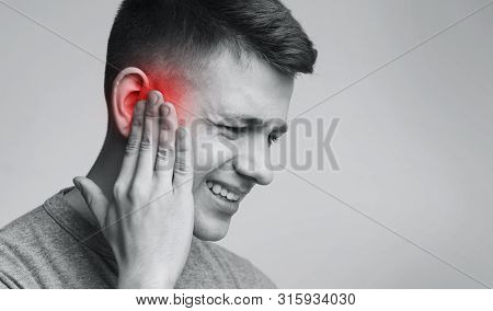 Acute Pain In Ear. Portrait Of Man Touching Inflamed Red Zone, Free Space