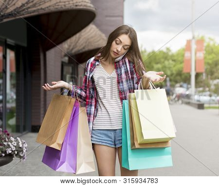 Sorry Honey, Ive Spent All The Money. Young Caucasian Woman Holding Colorful Paper Bags And Talking 