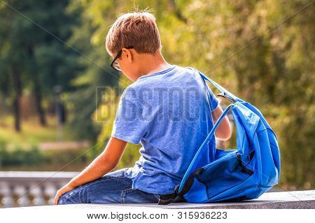 Tired Kid With Backpack Sitting Outdoors After School