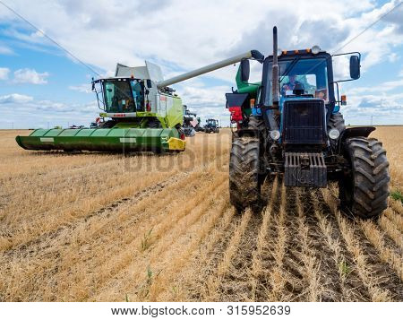 VILLAGE DECABRIST, SARTOV REGION, RUSSIA - AUGUST 03, 2019: Combine harvesters and tractors in the field for harvesting wheat