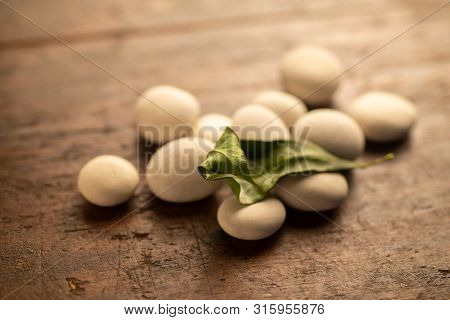 white fluvial stones and a dead leaf on a wooden table