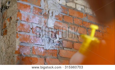 Priming Walls. Worker Primers The Wall With A Spray Gun. Pulverizer Soiled In Paint. Green Spray Gun