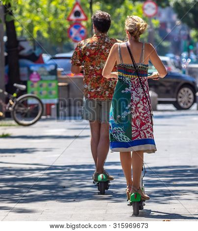 Bucharest, Romania - August 07, 2019: People Ride Lime-s Electric Scooters On A Sidewalk In Downtown