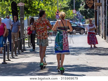 Bucharest, Romania - August 07, 2019: People Ride Lime-s Electric Scooters On A Sidewalk In Downtown
