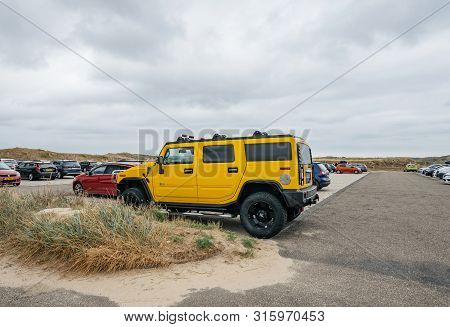 Overveen, Netherlands - Aug 16, 2019: Side View Of Luxury Yellow Hummer Large Suv Parked In The Sand