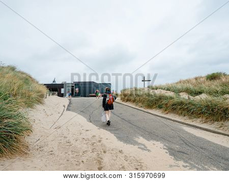 Overveen, Netherlands - Aug 16, 2018: Rear View Of Single Dutch Woman Walking To The Beach On A Clou