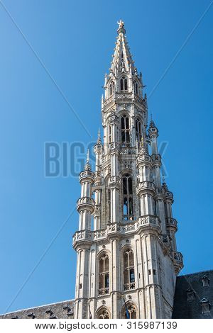 Brussels, Belgium - June 22, 2019: Closeup Of Gray Stone Spire Of City Hall On Grand Place Against B