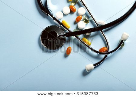 Scattered Color Pills And Phonendoscope On A Blue Background. Horizontal, Close-up, Free Space, No P