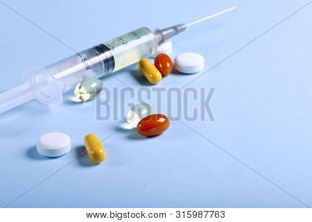 A Lot Of Bright Colored Medicine Pills And Syringe On A Blue Background. Cropped Shot, Horizontal, S