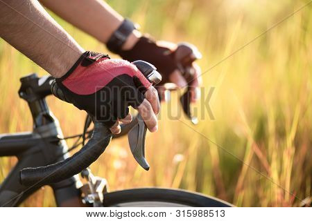 Hands In Gloves Holding Road Bicycle Handlebar. Sports And Outdoor Activities Concept.