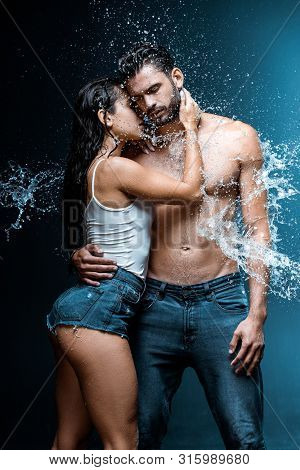 Sexy And Wet Woman Hugging Handsome And Muscular Boyfriend Under Raindrops On Black