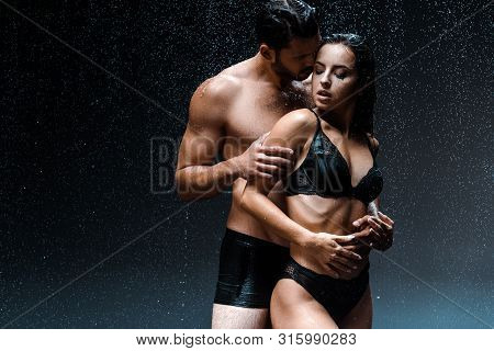 Shirtless Man Hugging Sexy And Wet Girl Under Raindrops On Black