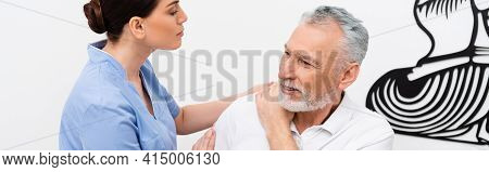Rehabilitologist Examining Middle Aged Man In Hospital, Banner.