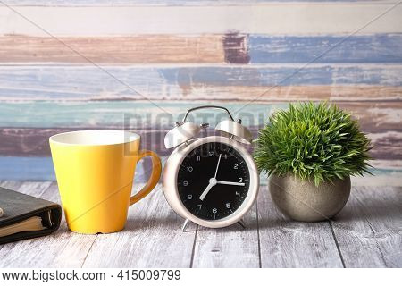 Coffee Mug, Notepad And Clock On Table Close Up