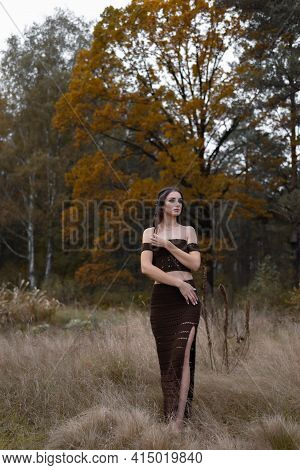 Tender Woman Dressed In Brown Dress, Embrasses Herself, Crosses Arms Over Body, Looks Away With Plea
