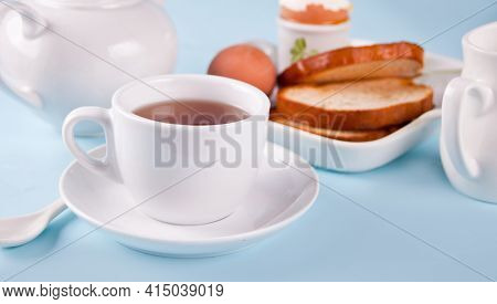 Cup Of Tea And Boiled Egg In Eggcup On Wooden Board With Crispy Toast. Breakfast Concept.