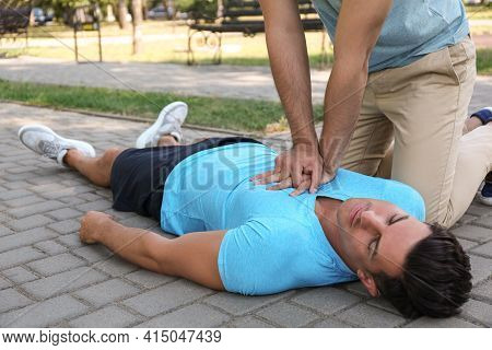 Passerby Performing Cpr On Unconscious Man Outdoors. First Aid