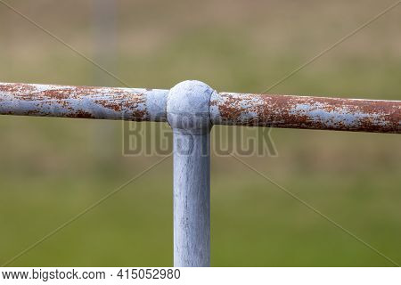 A Rusty Steel Galvanised Fence Post And Hand Rail On A Green Grass Background