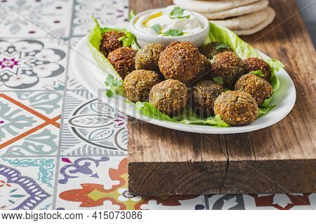 Traditional Homemade Chickpea Falafel Balls With White Sauce And Pita Bread On Whitw Plate On Wooden