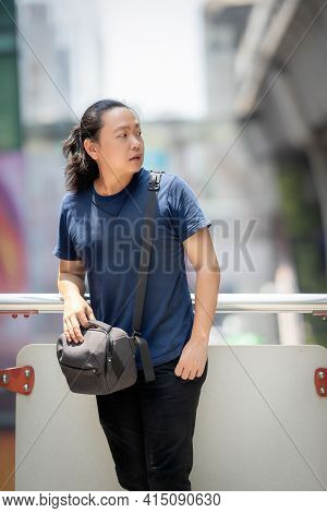 Asian Long Hair Man Looks At Beside Of His Posing At Outdoor Environment.