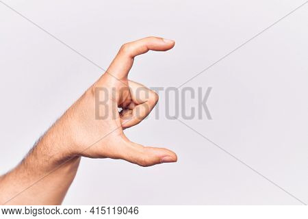 Close up of hand of young caucasian man over isolated background picking and taking invisible thing, holding object with fingers showing space 