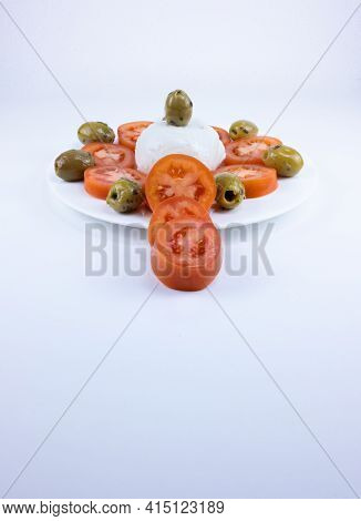 The Meal On A White Plate On A White Background Consists Of Sliced Tomatoes, Pitted Olives And Mozza