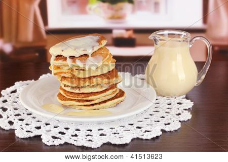 หวาน pancakes บนแผ่นกับนมข้นบนโต๊ะในห้อง