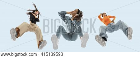 Young Stylish Women In Modern Street Style Outfit Isolated On Blue Background, View From The Bottom.