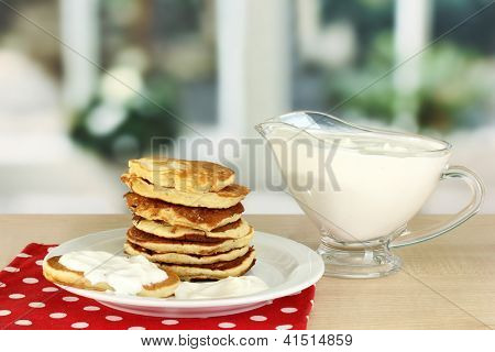 หวาน pancakes บนแผ่น ด้วยครีมเปรี้ยวบนโต๊ะในห้องครัว
