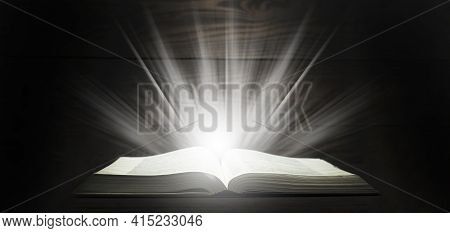 Open Bible. Rays Of Light Come Down From The Book. The Holy Book. On A Wooden Table