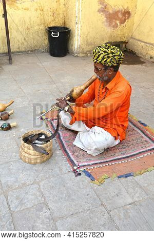 JAIPUR, INDIA - NOVEMBER 2, 2015: Snake charmer. Man plays his pungi to charm a cobra outside the Jantar Mantar monuments in India.