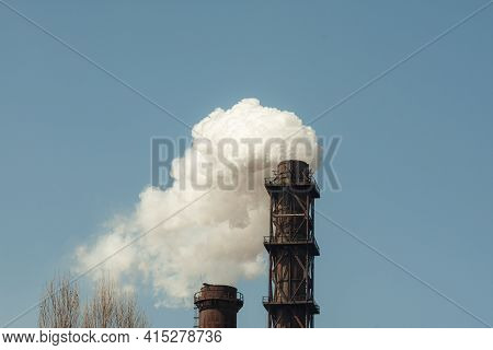 Two Industrial Pipes With Thick Smoke Coming Out Of Them.