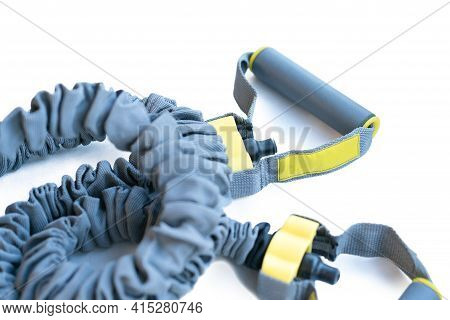 Grey And Yellow Handles Of Latex Resistance Band Scrunched In Nylon Safety Sleeve Isolated On A Whit