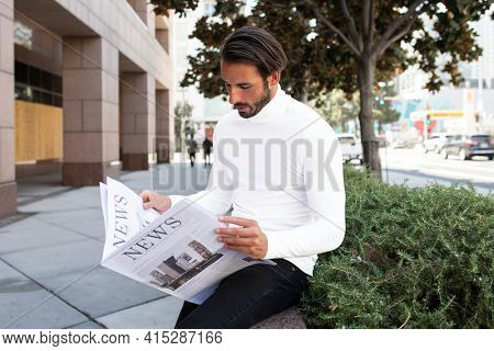 Businessman in turtleneck reading newspaper in the city