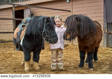 Girl And Pony. Child And Horses On Farm Paddock. Equestrian School. Hippotherapy