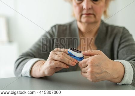 Pulse Oxymeter On A Woman Finger Hand On A Wooden Table. Top View.