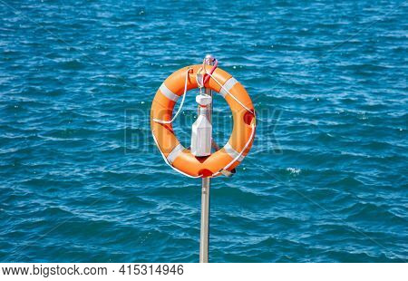 Buoy Concept. Lifebuoy, Orange Lifebelt Put On Silver Vertical Iron Ready For Using. Circle Lifesave