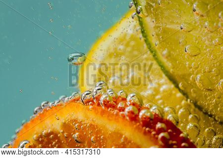 Bright, Juicy Orange Tangerines, Yellow Lemons, Lime Green In Water With Air Bubbles Behind Glass