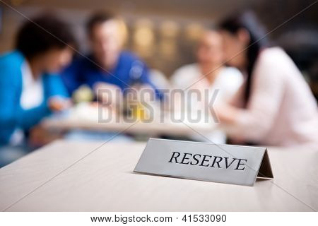 vyhrazený stůl v příjemné restauraci s hosty v pozadí
