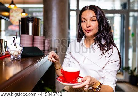 Circassian Reading Notes In Notepad While Sitting Near Table Bar And Drinling Cup Of Tea