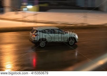 Russia, Moscow - January 2021: White Suv Car Rides On Wet Winter Road At Night. Side View Of Auto In