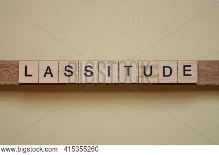 Text The Word Lassitude From Gray Wooden Small Letters With Black Font On An Brown Table