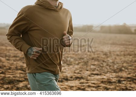Man in stretchy hoodie in the countryside at sunset