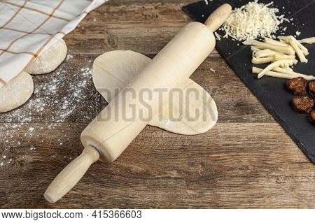 Closeup Image A Baker's Wooden Rolling Pin On  A Flattened Dough On Wood Kitchen Countertop. A Bread
