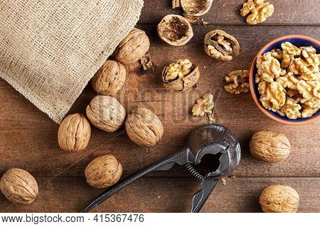 Flat Lay Image Showing A Cast Iron Walnut Pliers ( A Nutcracker Tool) With Raw Fresh Walnuts In Shel